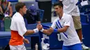 Petenis Serbia, Novak Djokovic, berjabat tangan dengan petenis Spanyol, Pablo Carreno Busta, pada AS Terbuka, di Flushing Meadows, Senin (7/9/2020). Djokovic didiskualifikasi karena memukulkan bola tenis ke arah hakim garis. (AP/Seth Wenig)