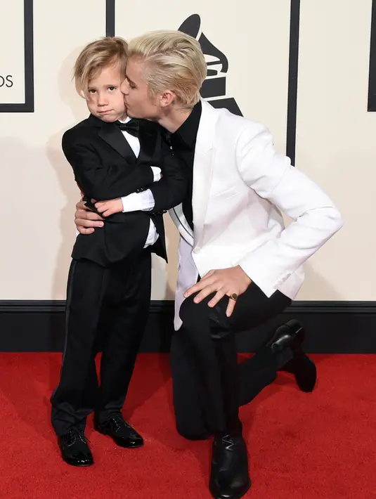 Justin Bieber mencium adiknya, Jaxon, saat berpose di karpet merah Grammy Awards 2016 di Staples Center, Los Angeles, Senin (15/2). Meski terpaut usia 15 tahun, namun Bieber  tampak dekat dengan sang adik. (Jason Merritt/Getty Images for NARAS/AFP)