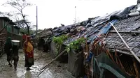 Pengungsi Rohingya berjalan di samping gubuk di sebuah kamp darurat di distrik Cox's Bazar di Bangladesh pada tanggal 30 Mei 2017 setelah Topan Mora mendarat di wilayah tersebut. (AFP Photo/Str)