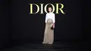 Charlize Theron mengenakan kemeja katun putih Dior di atas rok panjang Dior Haute Couture SS24 yang disulam dengan passementerie dalam kepang, jahitan bourdon, dan simpul emas mengilap. Dia juga mengenakan clutch, sepatu, dan perhiasan dari Dior. [Dior]
