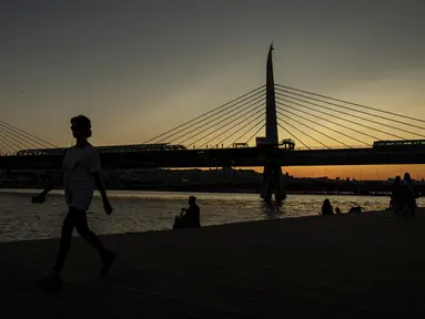 Seorang wanita berjalan di dekat the Golden Horn atau tanduk emas di Istanbul (26/7/2019). Tanduk Emas merupakan jalur air perkotaan utama dan pintu masuk utama Bosphorus di Istanbul, Turki. (AP Photo/Emrah Gurel)