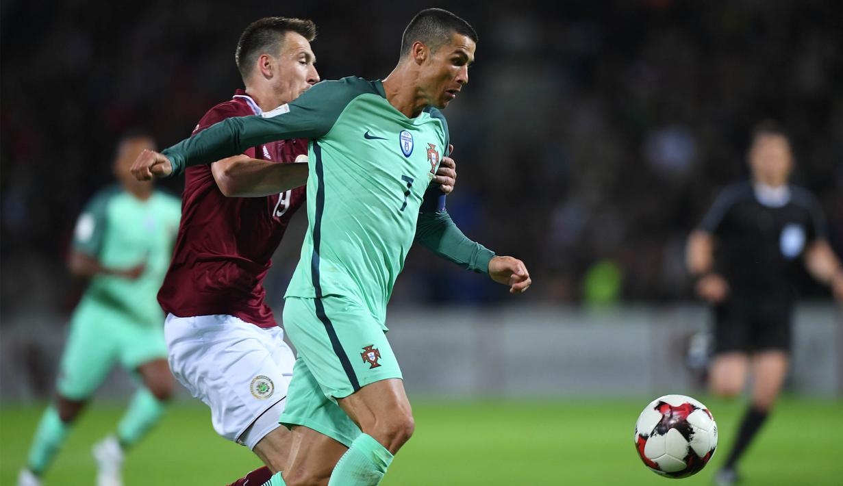 Bintang Portugal, Cristiano Ronaldo, berebut bola dengan bek Latvia, Vitalijs Jagodinskis, pada laga kualifikasi Piala Dunia 2018 di Stadion Skonto, Riga, Jumat (9/6/2017). Latvia kalah 0-3 dari Portugal. (AFP/Janek Skarzynski)