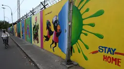 Seorang pria mengendarai sepeda melewati mural kesadaran virus corona COVID-19 di sepanjang pinggir jalan di Chennai, India, 13 September 2021. India bersiap hadapi kemungkinan lonjakan kasus COVID-19 sekitar musim festival September hingga November. (ARUN SANKAR/AFP)