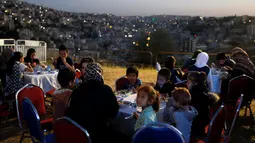 Sekelompok anak yatim dari kota utara Irbid berbuka puasa setelah menyaksikan penembakan meriam sebagai tanda berbuka puasa di Benteng Amman, 13 Mei 2019. Saat tiba waktu Maghrib yang sekaligus menjadi penanda waktu berbuka puasa di Yordania, ditandai dengan tembakan meriam. (REUTERS/Muhammad Hamed)