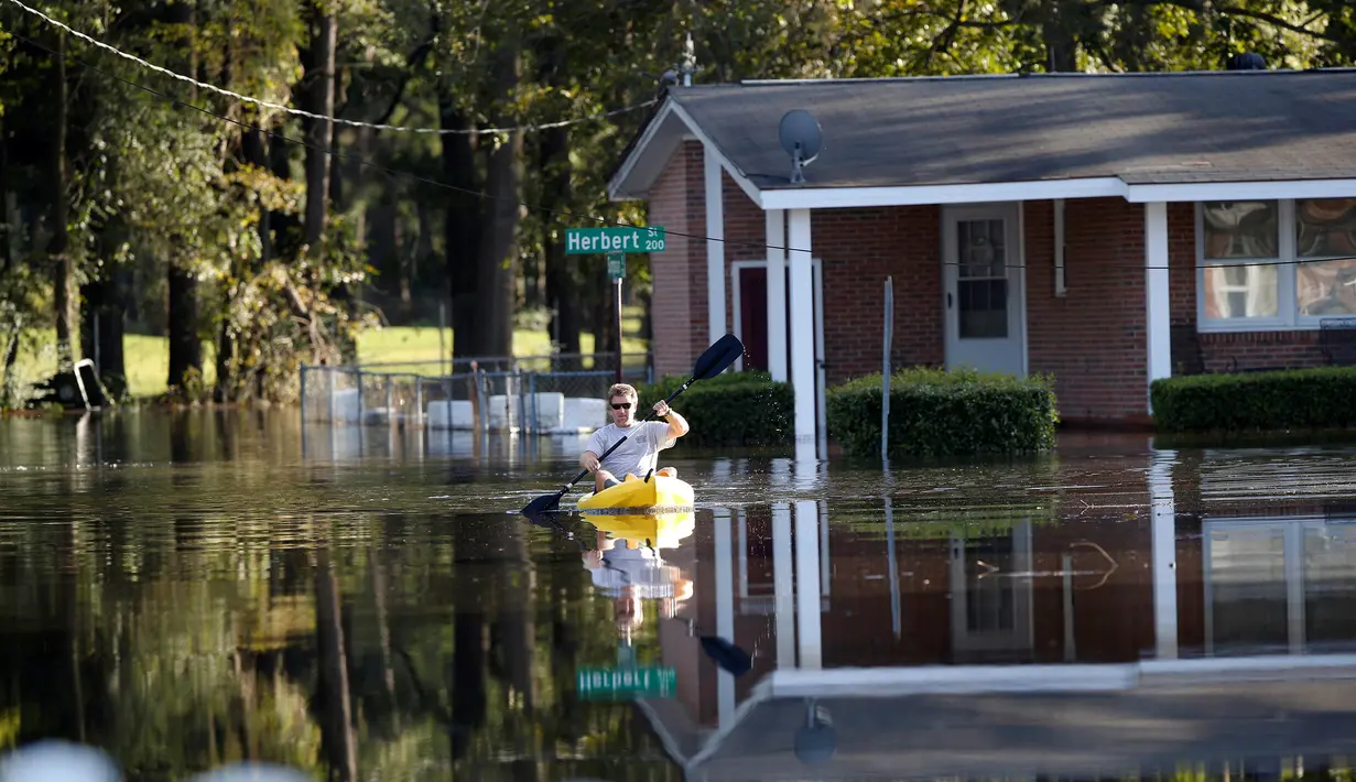 Parker Uzzell mendayung kano untuk melintasi banjir yang merendam wilayah Lumberton di Carolina Utara, Amerika Serikat, 12 Oktober 2016. Banjir akibat badai Matthew tersebut merendam kota berpenduduk 21.000 orang itu. (REUTERS/Randall Hill)