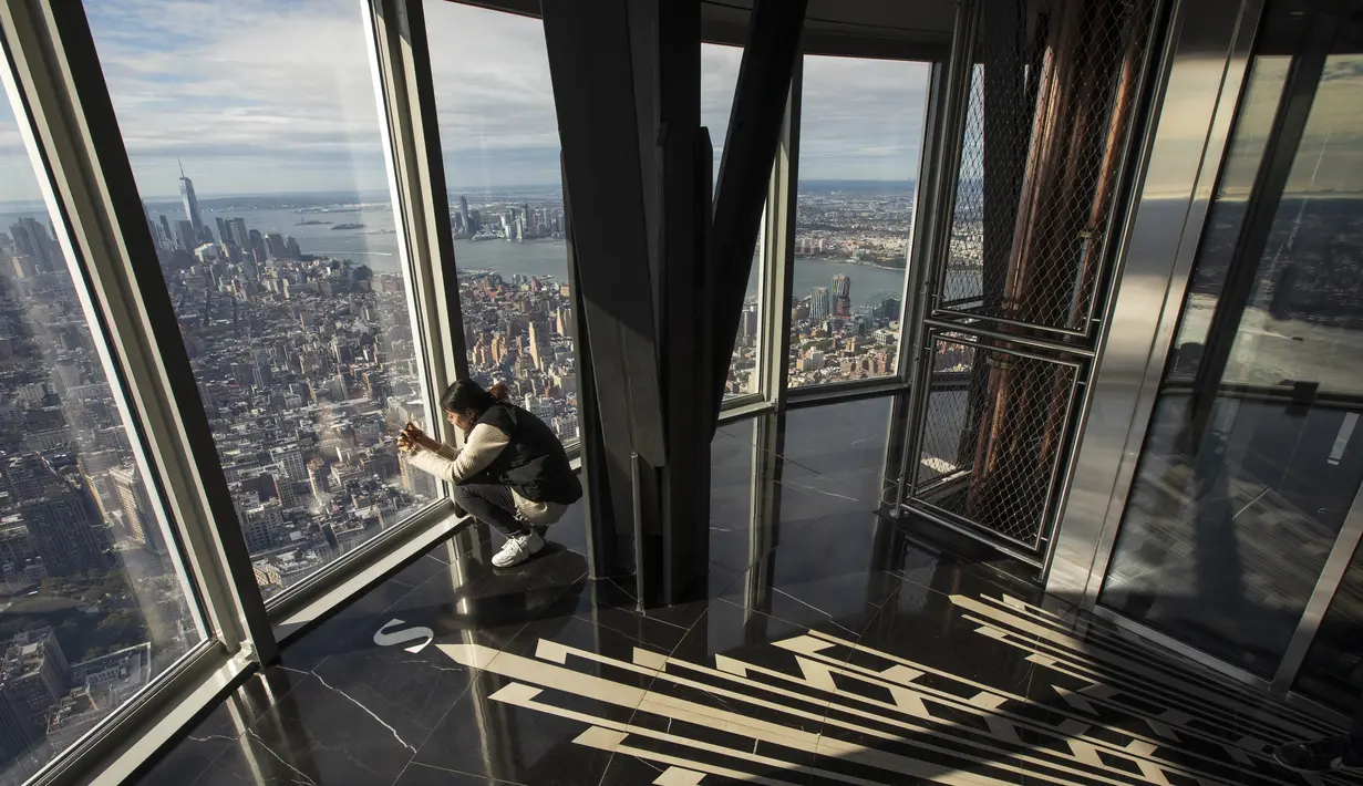 Seorang wanita mengabadikan suasana Kota Manhattan dari ruangan observatorium di lantai 102 Gedung Empire State yang baru direnovasi di New York (10/10/2019). Dibuka untuk umum pada 12 Oktober, ruang observatorium ini berjarak 1.250 kaki di atas permukaan jalan. (AFP Photo/Drew Angerer)