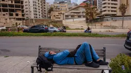 Intensitas serangan Israel menargetkan sejumlah wilayah di Lebanon, termasuk ibu kota Beirut dan wilayah perbatasan. Tampak dalam foto, seorang pria pengungsi tidur di bangku jalanan di Beirut pada 30 Maret 2026. Israel memperbarui pemboman pinggiran selatan Beirut, Lebanon, pada Senin 30 Maret 2026. (Dimitar DILKOFF/AFP)