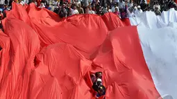 Bendera raksasa yang sengaja dibawa untuk mengiringi Kirab Budaya terlihat robek bagian tengahnya sehingga warga yang membawanya terlihat, Jakarta, Senin (20/10/2014) (Liputan6.com/Miftahul Hayat) 