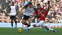 Pemain MU, Aaron Wan-Bissaka (kanan), berusaha menghalau bola dari pemain Fulham, Palinha (tengah) dalam pekan ke-11 Premier League 2023/2024 yang berlangsung di Stadion Craven Cottage, London, Sabtu (4/11/2023) malam WIB. (AFP/Adrian Dennis)