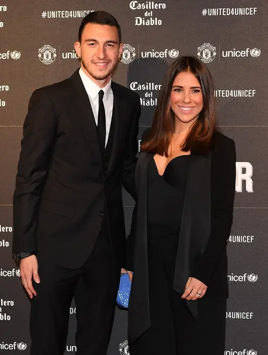 Bek Manchester United, Matteo Darmian menggandeng istrinya, Francessca Darmian di karpet merah makan malam acara amal UNICEF di Old Trafford, Rabu (15/11). Event ini sekaligus ajang pamer istri dan kekasih (WAGs) pasukan Red Devils. (Paul ELLIS/AFP)