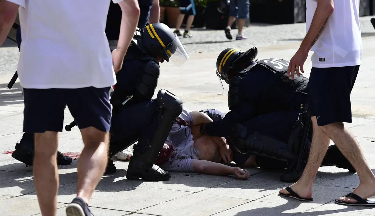 Polisi memeriksa kondisi seorang pria yang menjadi korban bentrok di kota Marseille, Prancis (11/6/2016). Bentrok terjadi menjelang pertandingan sepak bola Euro 2016 antara Inggris dan Rusia. (AFP Photo/ Tobias Schwarz)