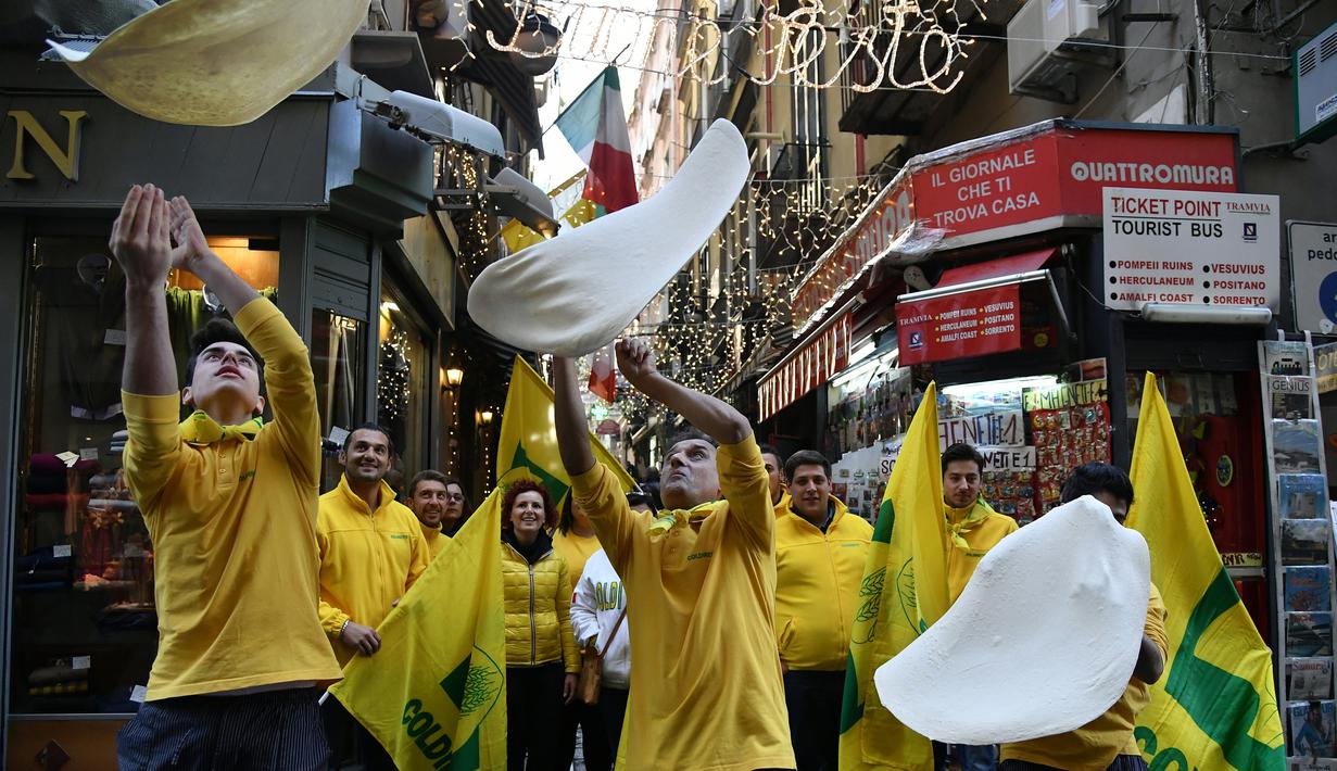 Anggota Pizzaioli Acrobats Coldiretti menunjukkan Pizzaioli untuk merayakan keputusan UNESCO di Naples, Italia, 7 Desember 2017. Pizzaioli adalah seni memutar adonan piza hingga mengembang dengan sempurna saat dipanggang. (Tiziana FABI/AFP)