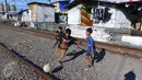 Anak-anak bermain bola di jalur kereta api di permukiman kampung bandan, Jakarta, Jumat (15/7). Badan Direksi Bank Dunia dan Bank Investasi Infrastruktur Asia (AIIB) menyetujui pemberian pendanaan sebesar US$ 433 juta. (Liputan6.com/Angga Yuniar)