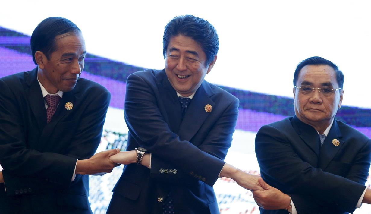 Presiden Jokowi (kiri) bergandeng tangan dengan  perdana Menteri Jepang Shinzo Abe dan Perdana Menteri Laos Thongsing Thammavong (ki-ka) pada KTT Asia Timur ( EAS ) ke 10 di Kuala Lumpur, Malaysia, (22/11). (REUTERS/Olivia Harris)