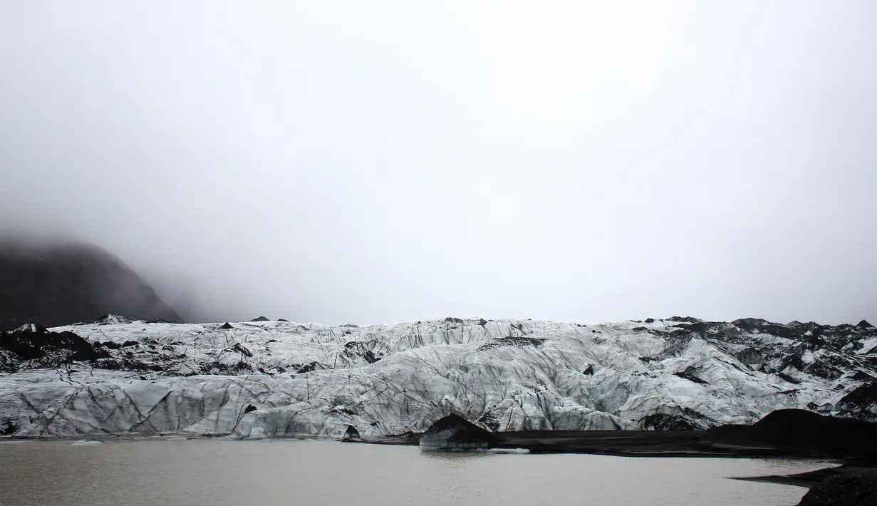 Turis berjalan saat mengunjungi perairan Gletser Solheimajokull, Islandia, Jumat (16/10).  Pemanasan global menyebabkan gletser Solheimajokull mencair hingga 1 km sejak pengukuran tahunan pada 1931. (AFP PHOTO/POOL/Thibault Camus)