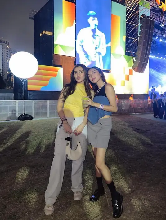 Pergi ke konser bersama sahabat, Aaliyah mengenakan atasan halter neck sleeveless kuning dipadukan celana abu-abu model cargo dengan gaya foto memanyunkan bibir sambil candid.[@aaliyah.massaid]