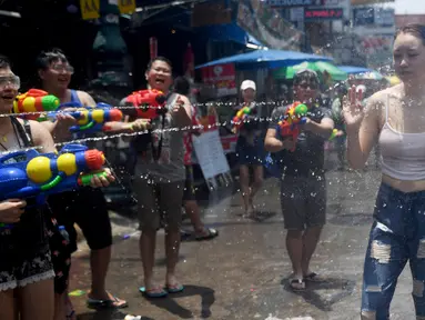 Warga menyemprotkan air ke seorang wanita saat merayakan Festival Songkran atau Tahun Baru Thailand di Bangkok, Thailand, 13 April 2019. Warga Thailand mengisi Festival Songkran dengan bersenang-senang, salah satunya perang air. (Lillian SUWANRUMPHA/AFP)