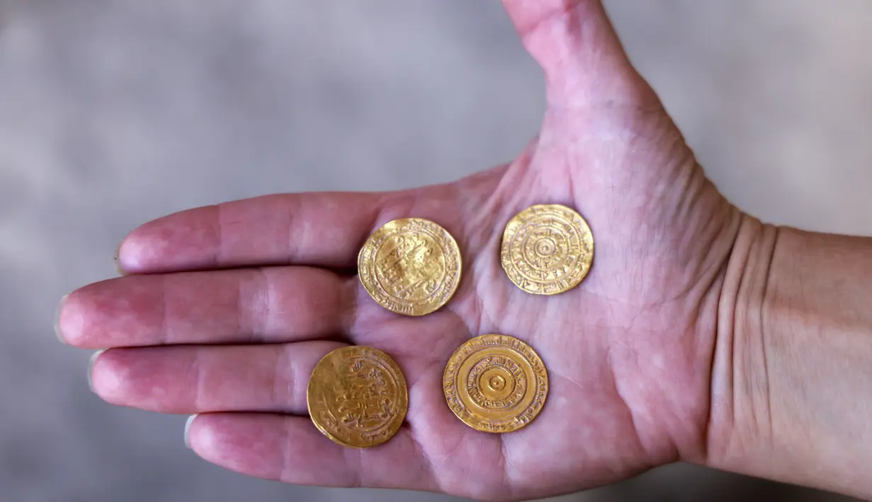 Arkeolog Israel Antiquities Authority menunjukkan empat koin emas murni dari dalam kendi tembikar di Kota Tua Yerusalem, Senin (9/11/2020). Kendi tembikar berusia 1.000 tahun yang berisi empat koin emas dari periode awal Islam, ditemukan di dekat Plaza Tembok Ratapan. (MENAHEM KAHANA/AFP)