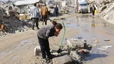 Warga Palestina yang mengungsi hidup di tengah reruntuhan rumah dan bangunan yang hancur akibat serangan militer Israel selama lebih dari dua tahun di wilayah Gaza, minum air dari keran umum, di kamp pengungsi Jabalia, di Jalur Gaza utara pada Sabtu 17 Januari 2026. Gedung Putih membentuk Komite Nasional untuk Administrasi Gaza (National Committee for the Administration of Gaza/NCAG) dan Dewan Perdamaian Gaza. (Omar AL-QATTAA/AFP)
