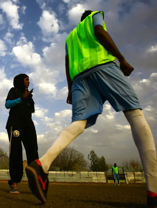 Salma al-Majidi melihat para pemain klub Al-Ahly Al-Gadaref selama sesi pelatihan di kota Gedaref, timur Khartoum (17/2). Salma diakui FIFA sebagai wanita Arab dan Sudan pertama yang melatih tim sepak bola pria Arab. (AFP Photo/Ashraf Shazly)