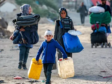 Seorang anak laki-laki berjalan dengan jeriken kosong bersama orang-orang yang mengungsi akibat konflik dan melarikan diri dari Beit Hanun, Jalur Gaza utara tiba di Kota Gaza pada 18 Maret 2025. (Bashar TALEB/AFP)