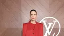 Jennifer Connelly tampil serba merah mengenakan atasan lengan panjang dengan kerah pita dipadukan mini skirt berpita samping. Sambil membawa bucket bag LB coklat dan heels strap warna-warni. [dok. Louis Vuitton]