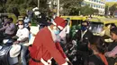 Presiden Angel Foundation dan pekerja sosial, Rufas Christian, yang berpakaian Sinterklas memakaikan masker kepada seorang anak di persimpangan lalu lintas di Ahmedabad, India, Kamis (17/12/2020). Aksi itu sebagai bagian dari kampanye kesadaran melawan penyebaran COVID-19. (SAM PANTHAKY/AFP)