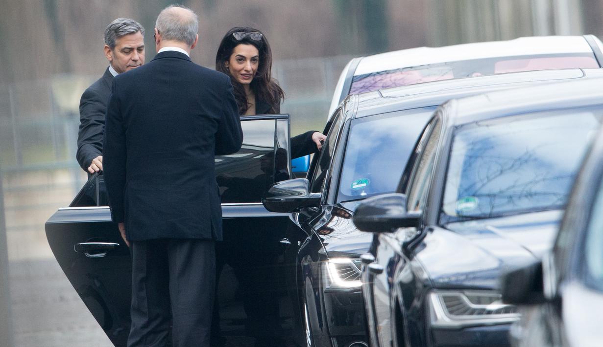 Aktor AS, George Clooney dan istrinya, Amal Alamuddin bersiap meninggalkan Kanselir Jerman di Berlin, Jerman, Jumat (12/2). Clooney dan istrinya menemui Kanselir Jerman, Angela Merkel guna membahas krisis pengungsi di Eropa. (Kay NIETFELD/DPA/AFP)