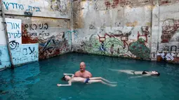 Wisatawan berenang di kolam air panas di ujung selatan Dataran Tinggi Golan yang dianeksasi Israel, dekat perbatasan dengan Yordania, 1 Maret 2019. Kolam dengan air panas itu berasal dari aliran pipa pengeboran di Lembah Hula. (MENAHEM KAHANA/AFP)