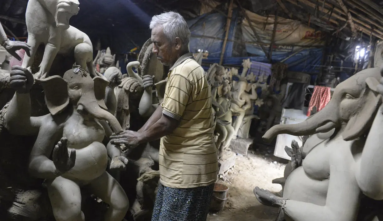 Perajin membuat patung Dewa Ganesha di sebuah bengkel di pinggiran Hyderabad, India, Rabu (18/8/2021). ​Patung ramah lingkungan yang dibuat jelang perayaan Ganesh Chaturthi tersebut dibuat dari lumpur, serat rami, dan bambu untuk mengurangi polusi air. (NOAH SEELAM/AFP)
