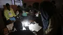 Para petugas pemilu bekerja, menghitung jumlah suara di sebuah Tempat Pengumutan Suara (TPS) di Port-au-Prince, Haiti (20/11). Pemilu ini tertunda akibat bencana alam dan ketidakstabilan politik yang terjadi di Haiti. (Reuters/Jeanty Junior Augustin)