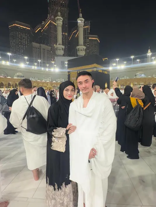 Momen berikutnya memperlihatkan keduanya berpose mesra di depan Ka'bah. Putri Zulhas tampil anggun dalam gamis putih dengan aksen renda emas yang memberikan kesan mewah namun tetap sopan.  [@zumizolazulkiflinurdin].