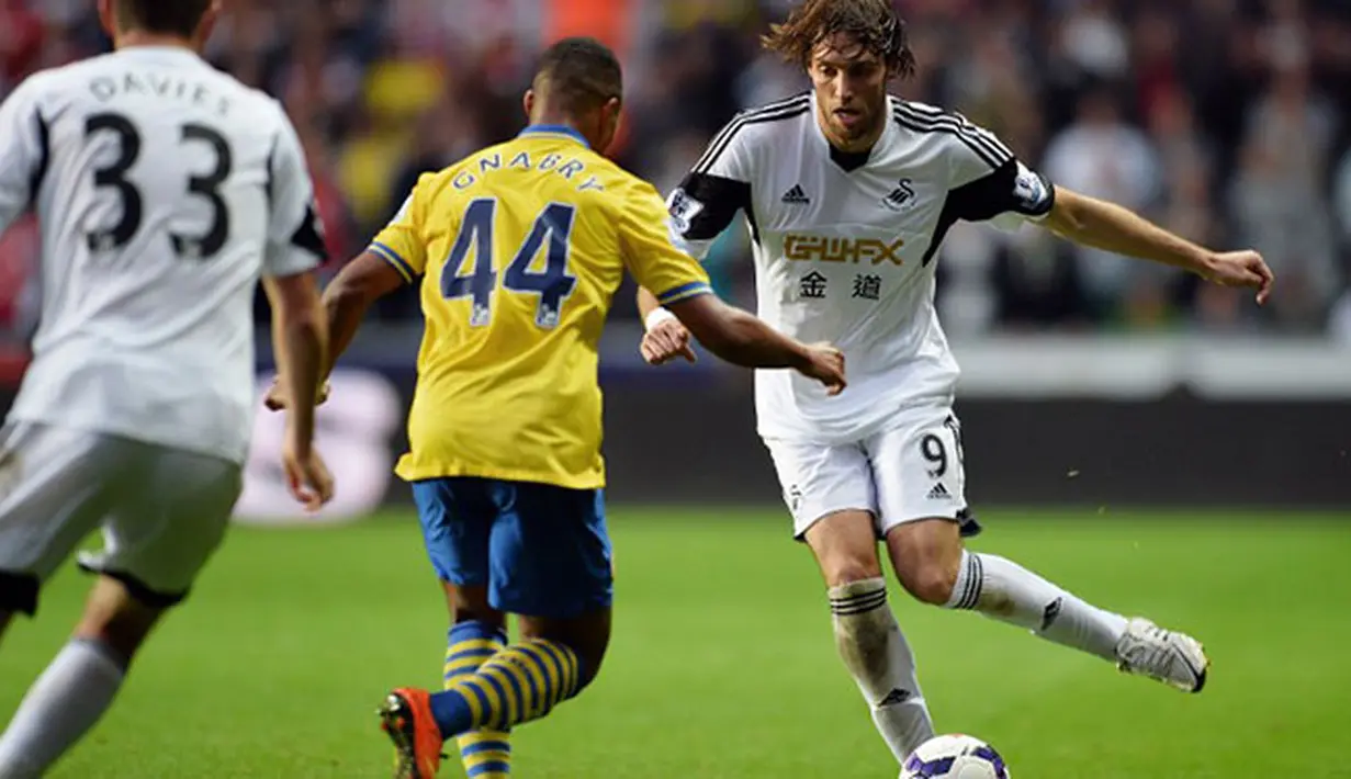 Pemain Swansea City Miguel Michu duel dengan Pemain Arsenal Serge Gnabry Pada pertandingan Liga Premier Inggris antara Swansea City dan Arsenal di Stadion Liberty di Swansea (28/09/13). (AFP/Paul Ellis)