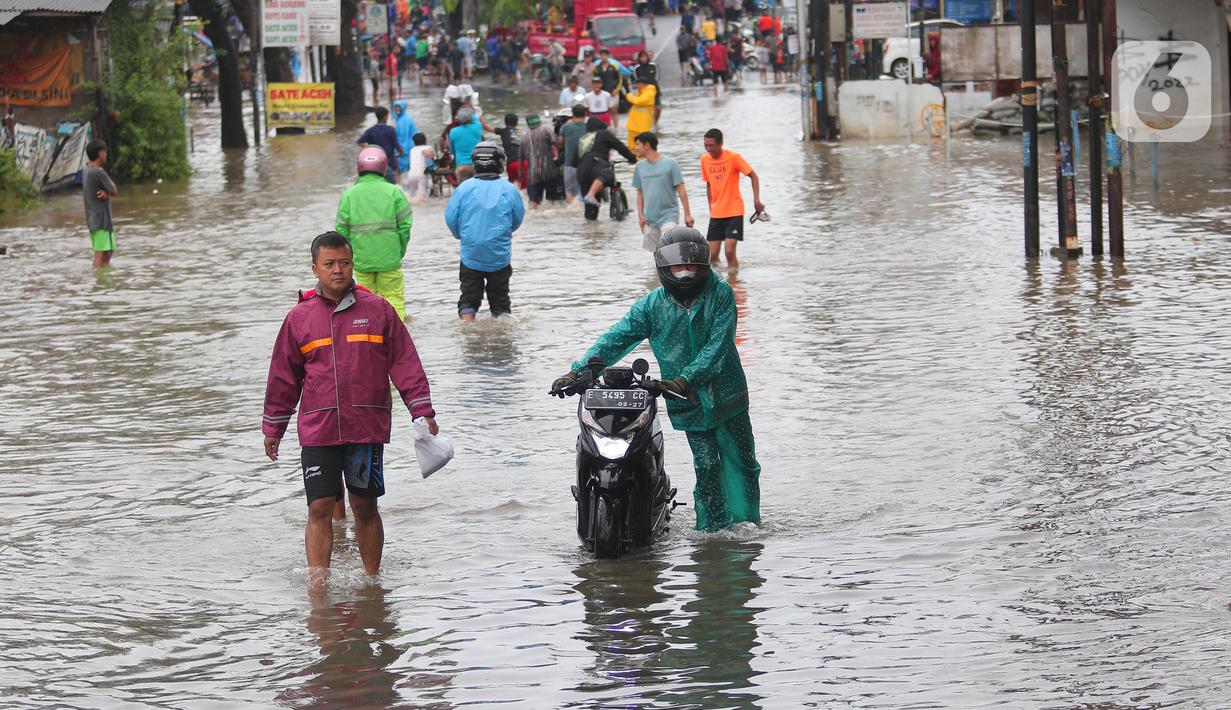 Pengendara motor mendorong kendaraannya melintasi genangan air ketika banjir merendam Jalan KH. Hasyim Ashari, Tangerang, Banten, Sabtu (16/7/2022). Hujan deras mengguyur sejak Jumat siang hingga Sabtu pagi. (Liputan6.com/Angga Yuniar)