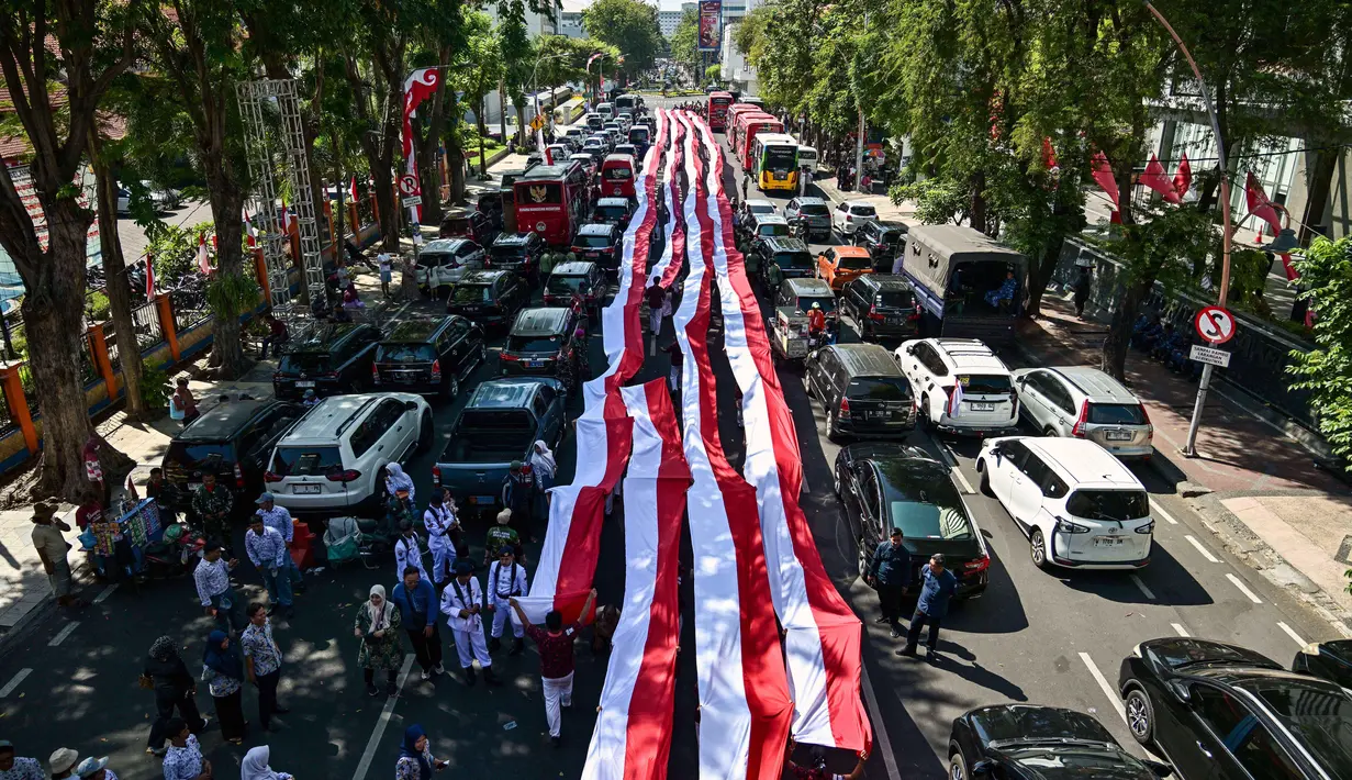 Diketahui, Kota Surabaya di Jawa Timur yang menjadi salah satu kota besar di Indonesia turut serta dalam memeriahkan HUT ke-80 Kemerdekaan dengan berbagai kegiatan, termasuk upacara dan arak-arakan bendera Merah Putih. (Juni KRISWANTO/AFP)