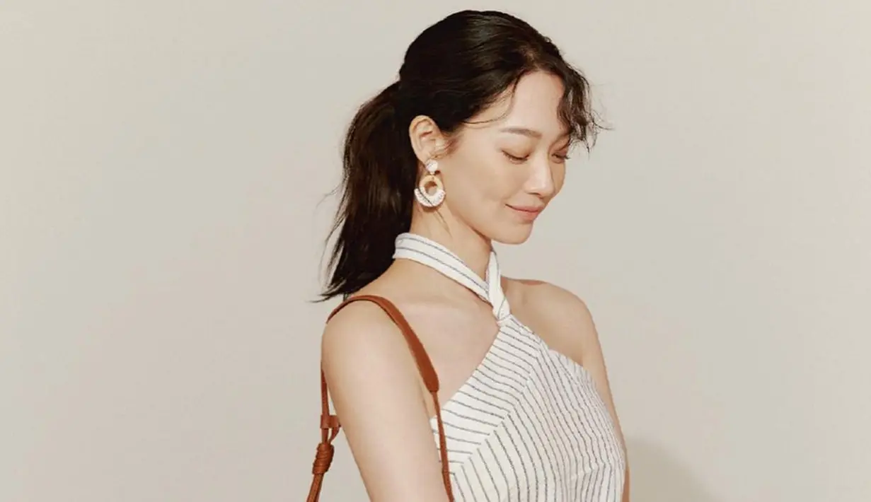 Simple dress tanpa lenagan yang dikenakan oleh Shin Min Ah satu ini pun terlihat begitu menawan. Ia pun memilih memadukan dengan anting sederhana serta sling bag cokelat. (Liputan6.com/IG/@illusomina)