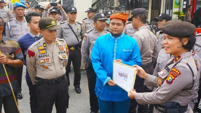 Aktivis Walhi menyerahkan data sebaran titik panas indikasi kebakaran lahan di konsesi perusahaan ke Polda Riau.