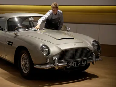 Seorang staf berpose dengan Aston Martin DB5 yang digunakan dalam film James Bond GoldenEye tahun 1995 di rumah lelang Bonham, London, Selasa (19/6). Mobil legendaris yang dikemudikan aktor Pierce Brosnan itu bakal dilelang pemiliknya. (AP/Matt Dunham)