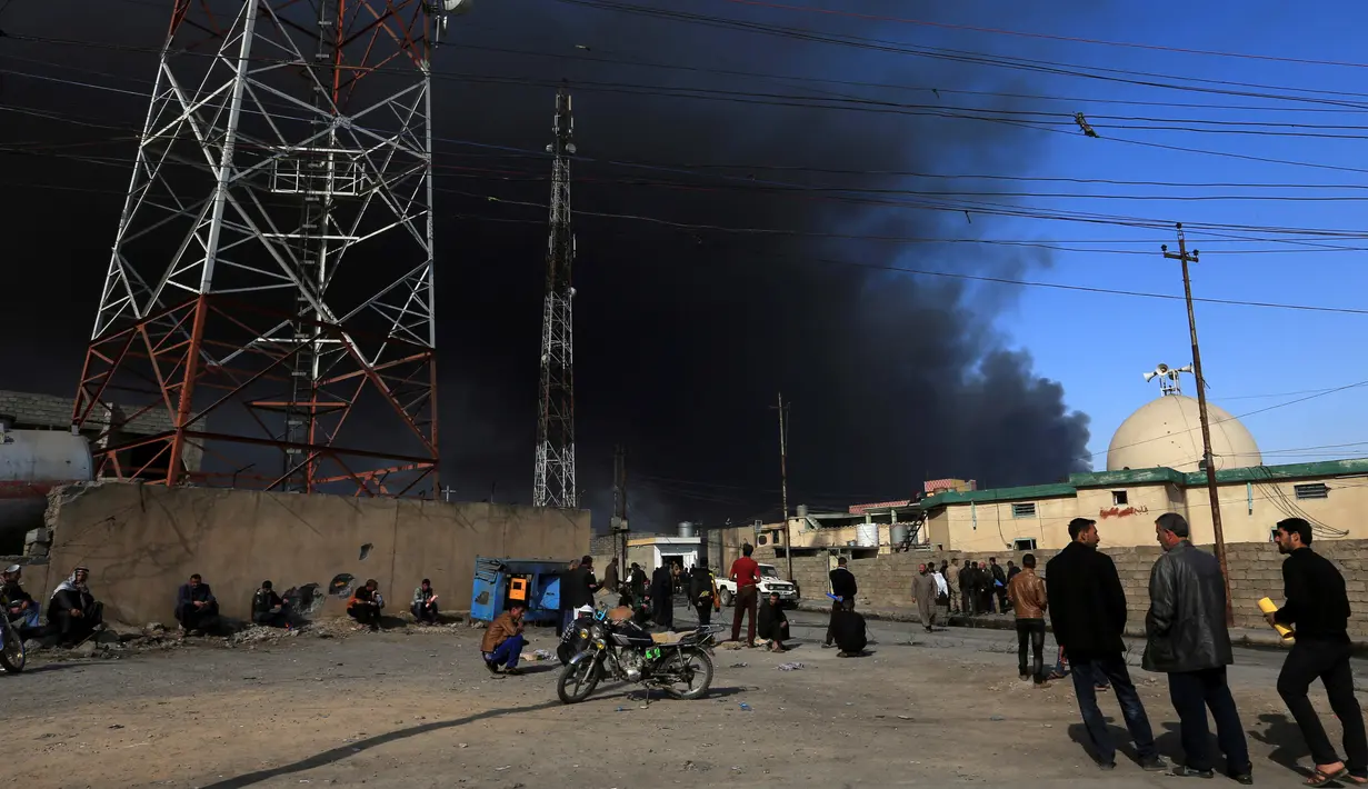 Warga berkumpul melihat kepulan asap hitam akibat dari terbakarnya pabrik kimia yang dibakar oleh militan ISIS di Qayyara, Irak, (12/11). (REUTERS/Air Jalal)