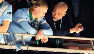Momen Pep Guardiola (kanan) berbincang dengan Erling Haaland usai menerima medali juara Carabao Cup. Pada partai final, Man City mengalahkan Arsenal 2-0. (Adrian Dennis / AFP)