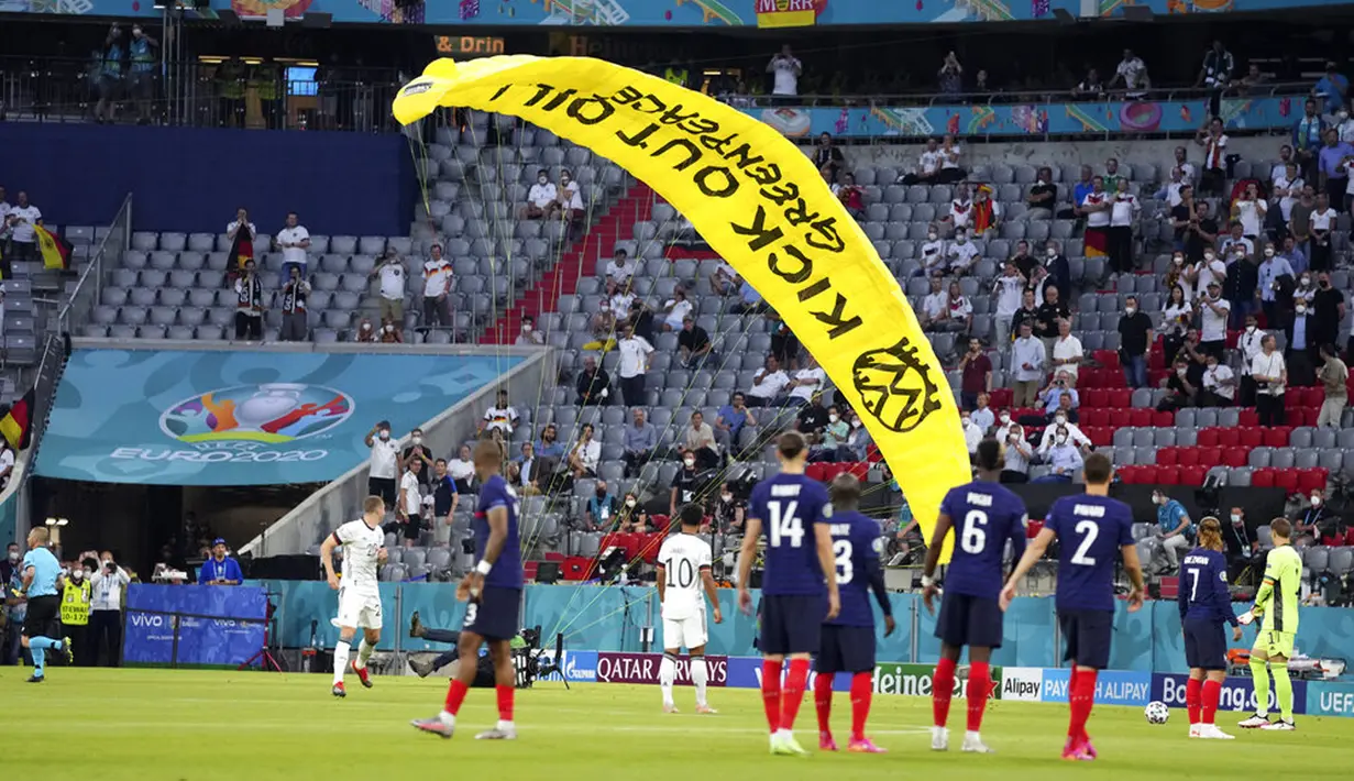 Paraglider Greenpeace mendarat di lapangan sebelum pertandingan Grup F Euro 2020  antara Prancis dan Jerman di Allianz Arena, Munich, Jerman, Selasa (15/6/2021). Sang aktivis kemungkinan mengalami patah tulang engkel ketika mendarat. (AP Photo/Matthias Schrader, Pool)