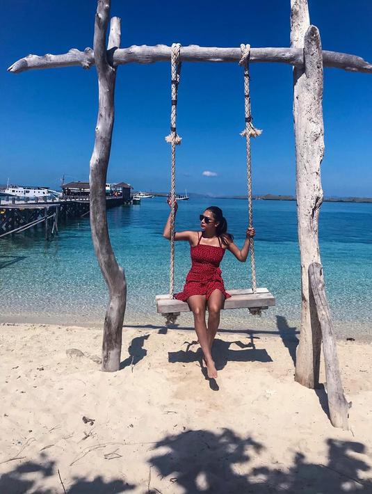 Semakin maksimal, busana liburan di wisata alam Mey Chan pun turut menyesuaikan. Mey Chan nampak menikmati terik matahari di Pulau Kenawa. Mey Chan hanya mengenakan dress simpel berwarna merah dengan kaca mata hitamnya sambil menikmati birunya air pantai. (Liputan6.com/IG/@ditaofficial.id)