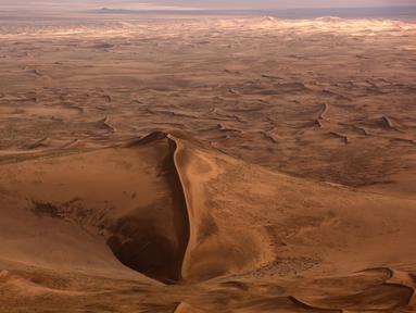 Pandangan dari udara sebuah bukit dikelilingi hamparan pasir Gurun Gobi wilayah Mongolia (21/7). Gurun terbesar di Asia ini sangat menakjubkan ketika dilihat dari udara. (AFP PHOTO / PATRICK BAZ)