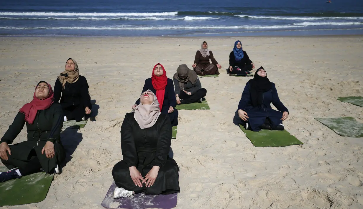Sejumlah wanita Palestina berlatih yoga di pantai di Gaza City (3/3/2020). Pelatihan yoga tersebut diselenggarakan oleh Positive Energy Club. (AFP Photo/Mohammed Abed)