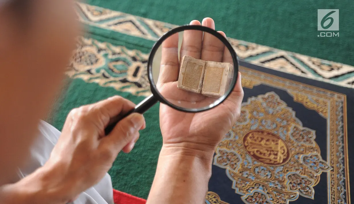 Kyai Tubagus Muhammad Tamyiz membaca Alquran mini bertinta emas dengan bantuan kaca pembesar di Masjid Jami Darusalam, Sukaraja, Bogor, Jawa Barat, Kamis (24/5). Alquran mini tersebut berukuran 10 mm x 10 mm. (Merdeka.com/Arie Basuki)
