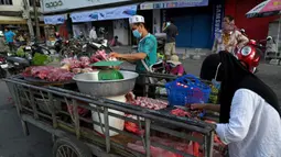 Pedagang menyiapkan daging untuk dijual di sepanjang jalan karena pasar tetap tutup di tengah pembatasan lockdown yang diberlakukan untuk mencoba menghentikan lonjakan kasus virus corona COVID-19 di Phnom Penh, Kamboja, Selasa (11/5/2021). (TANG CHHIN Sothy/AFP)
