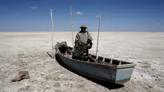 Seorang nelayan dari kelompok etnik Urus berdiri di atas perahunya yang tergeletak di Danau Poopo, La Paz, Bolivia, (17/12). Banyak nelayan kehilangan pekerjaannya akibat keringnya danau ini. (REUTERS/David Mercado)