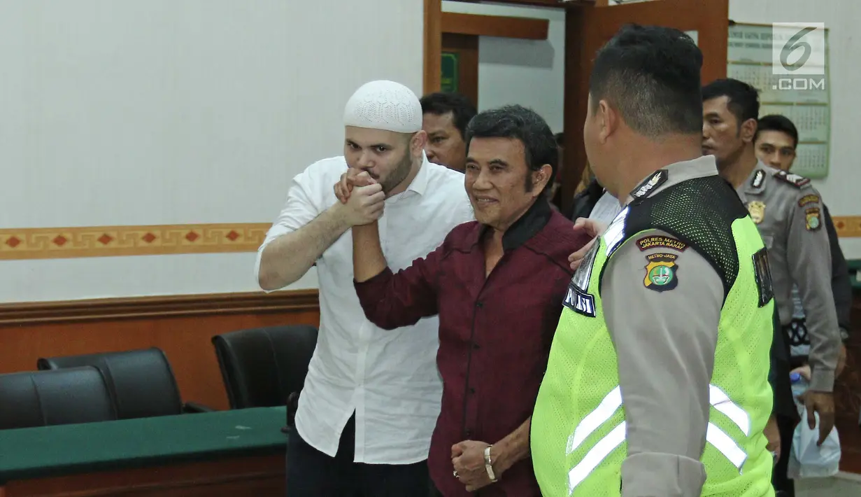 Ridho Rhoma mencium tangan Rhoma Irama usai menjalani sidang putusan di PN Jakarta Barat , Selasa (19/9). Ridho Rhoma divonis 10 bulan penjara dipotong masa tahanan dan menjalankan Rehabilitasi di RSKO. (Liputan6.com/Herman Zakharia)