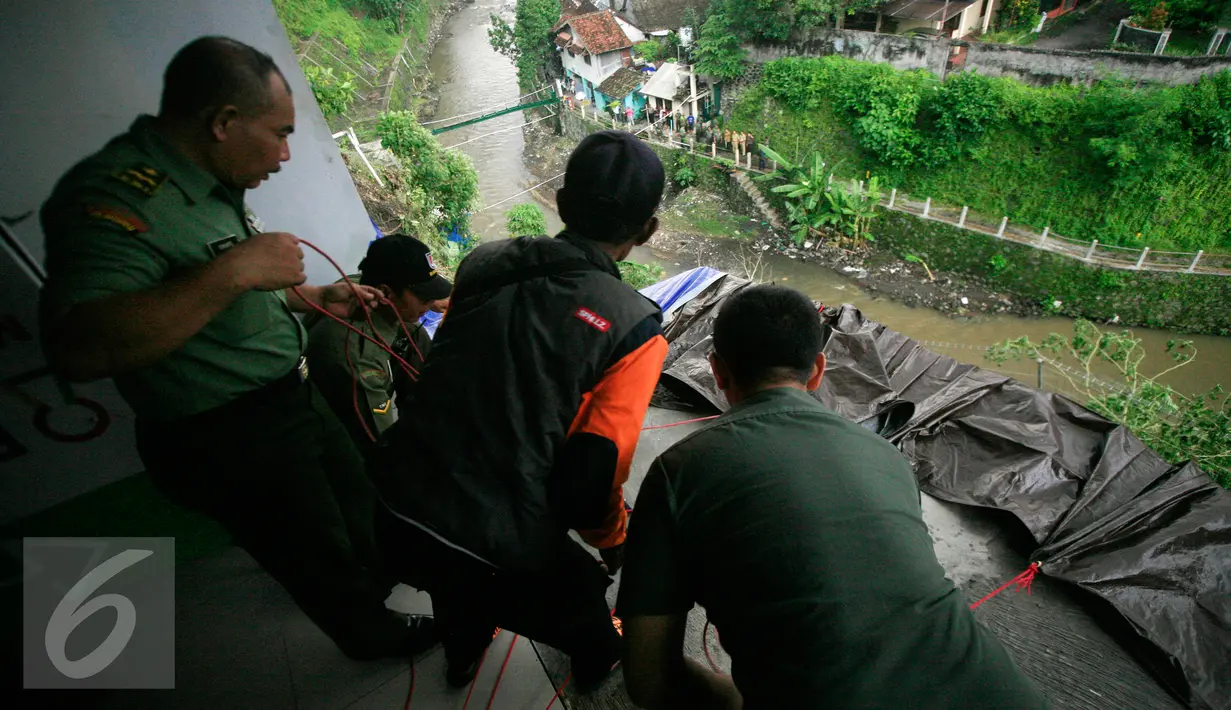 Tim SAR bersama TNI memasang terpal untuk mengantispasi terjadinya longsor susulan di bantaran Kali Code, Yogyakarta, Rabu (30/3). Longsor terjadi akibat hujan deras yang terjadi pada pagi hari. (Liputan6.com/Boy Harjanto)