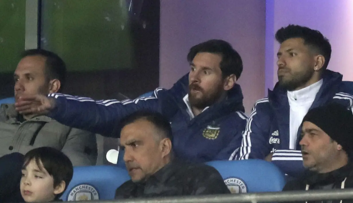 Lionel Messi (tengah) dan Sergio Aguero saat menjadi penonton di tribune pada laga uji coba Argentina melawan Italia di Etihad Stadium, Manchester, Inggris, (23/3/2018). Argentina menang atas Italia 2-0. (Martin Rickett/PA via AP)